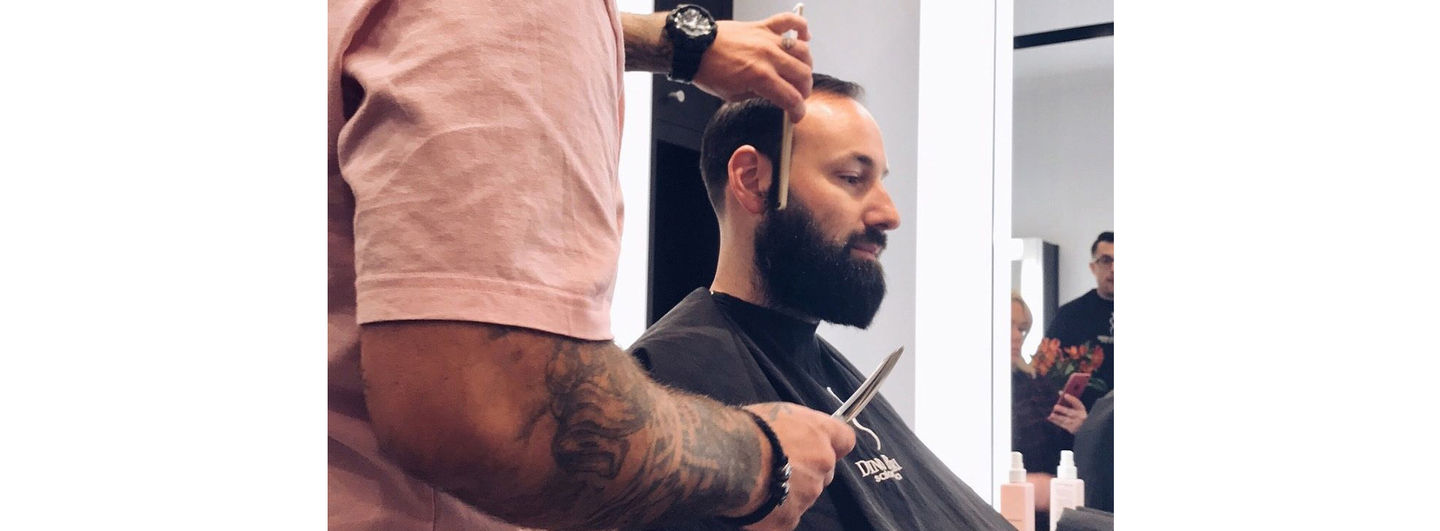 Professional barber grooming a man's beard.